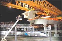 Photograph of the placement of a bridge segment by use of an erection gantry.