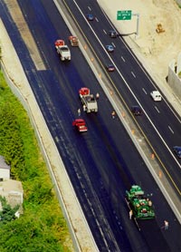 Figure 1. Photo. Highway construction. Several construction workers and vehicles are scattered on the left side of the highway while two other vehicles travel on the opposite side.