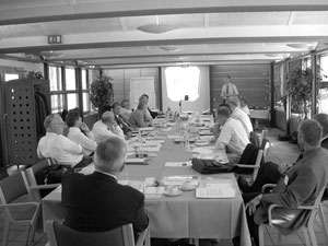 Figure 6. Photo. Scanning tour panel members assembled for a meeting. Several scanning tour panel mambers are seated at a long conference table strewn with documents.