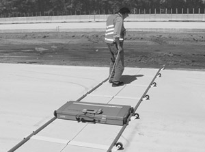 Figure 17. Photo. MIT Scan-2 in use. Individual is handling the MIT Scan-2 device as it rides on tracks and is pulled across concrete.