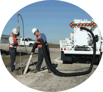 This picture depicts 'locating' and shows operators exposing subsurface utilities by digging a test hole using an air hose to loosen the soil and nondestructive vacuum excavation to remove the soil.