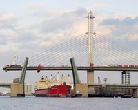 Unidirectional cantilever erection, precast concrete delta frames and an innovation cable stay cradle system allowed for rapid construction of the main span. In this image, it is evident where glass will be installed on the upper 196’ of the pylons.