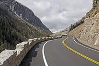 Stone guardwall accentuates the curvilinear alignment as the East Entrance Road enters Sylvan Pass. Widened and deepened ditches along the erosive cut slopes minimize rockfall hazards.