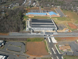 Aerial view of the finished parking structure, the top of which has become a grass playing field for the neighboring school.