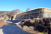 Photo taken from Pine Creek showing the retaining wall and rock cut-slope from below.