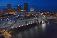 Night view of the bridge with decorative lighting emphasizing the arch and the fanned cables.