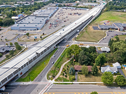 Photo of elevated, four-lane expressway, with combination retaining/noise walls and bridges over the local cross streets.