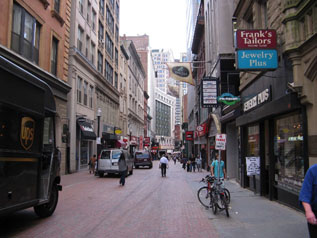 Photo of a shared street with pedestrians and motor vehicles mixing in the central space.
