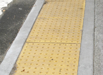 Photo of a yellow detectable warning surface with round truncated domes.