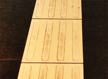 Photo of a yellow directional indicator with elongated raised bars.