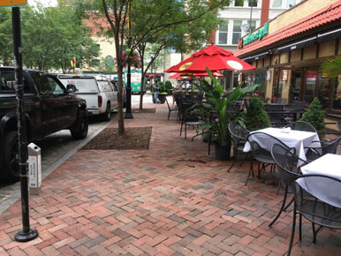 Photo of the comfort zone on the shared street that includes cafe seating. The seating creates a pinch point in the comfort zone that looks to be approximately three feet wide.