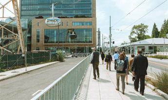 Photograph of people walking along a path adjacent to a roadway separated by a waist high fence.