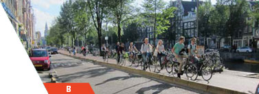 A large group of of bicylists riding alongside a road.