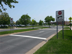 Image is of signage in use for pedestrians: Stop Here For Pedestrians.