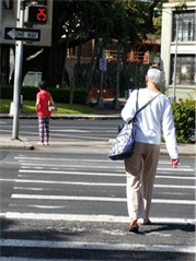 Image is of pedestrians on crosswalk with faded markings.