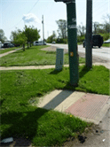 Image is of a curb cut and pedestrian signal with no adjoining sidewalk.