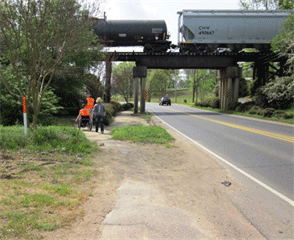 Image shows pedestrians walking under a rail bridge in a constrained right of way.