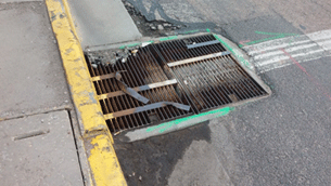 Image shows a poorly oriented and maintained drainage grate.