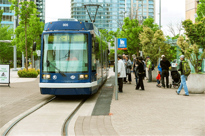 Image shows people at a transit station area approaching a streetcar.