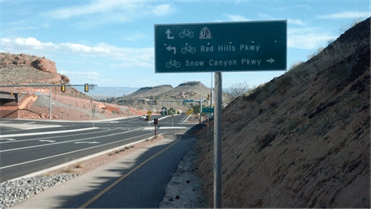 Image shows a multi-use path along a divided highway in a rural setting.