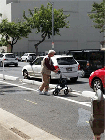 Image shows pedestrian using a mobility device negotiating a difficult roadway crossing.