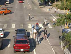 Photo of bicyclists and cars at an intersection.