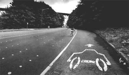 Edited Photo of a road with main lanes being bicycle lanes and shoulder accessible to cars.