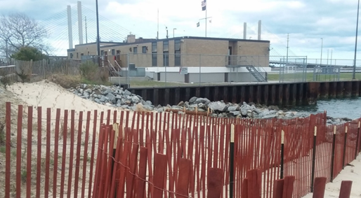 Sand fencing, dune, riprap, sheetpile bulkhead, and brick building.