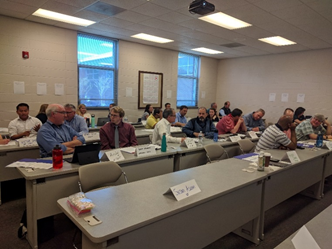 Peer exchange participants pair off to discuss. Rows of tables are angled diagonally with visible table tents.