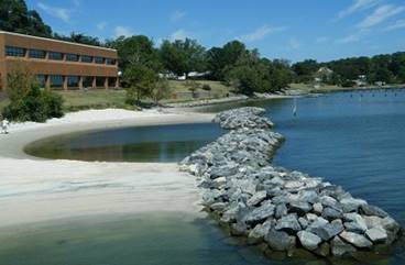 Photograph of a rocky bulkhead stretching parallel to a beach.
