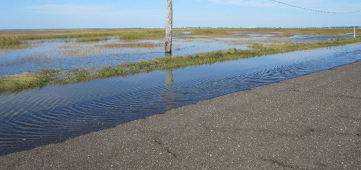 Photograph showing flooding of a coastal roadway travel lane, roadway shoulder.