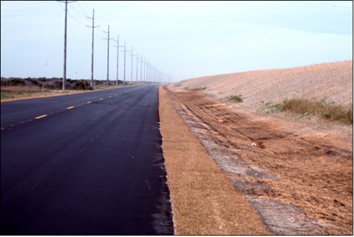 Photograph of an artificially constructed dune protecting a coastal highway along a barrier island.