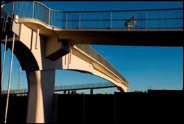 Glenmore Trail/Legsby Pedestrian Bridge, Alberta (2007) is a single span, 53 m bridge that crosses 8 lanes of traffic, consisting of 2 cantilevered, high performance concrete abutments and a 33.6 m drop-in, T-section Ductal ® girder. The girder required 40 m^3 of material and the largest, single monolithic pour of Ductal® in the world to date. This project won a Precast/Prestressed Concrete Institute (PCI) Special Jury Award for Innovative Technology and 2 American Concrete Institute (ACI) Awards of Excellence in Concrete