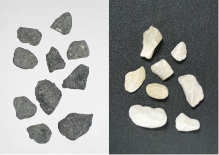 Figure 2.1. Photo. Dark and light 9.5 mm (0.375 in) aggregates used in Experiment 1. A white rectangle and a dark rectangle are shown side by side. On the white rectangle, several pieces of dark aggregate are shown; on the dark rectangle, several pieces of light-colored aggregate are shown.