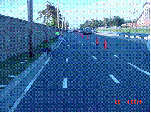 This picture shows a general northbound view of the street, which is now the test deck, taken from eye height. Several skip lines on the edgeline, centerline and the wheel track positions are seen on the right lane. Left lane has no test marking installations.