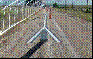 This picture shows a northbound view of the rain tunnel with an installed marking in view. Both ends of the test marking are open and blask masking tapes can be seen on the roadway, which are used to cover the lane shift extensions (tapers).