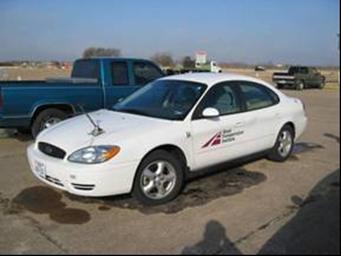 This picture shows a general view of the test vehicle, which is a white Ford Taurus sedan.