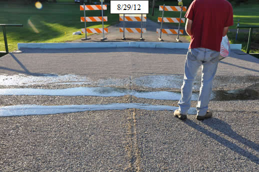 Figure 28. Photo. Spread crushed stone aggregate for second course of wearing surface. Then install 1-inch foam backer rod at the bottom of the begin and end bridge joints (not pictured).