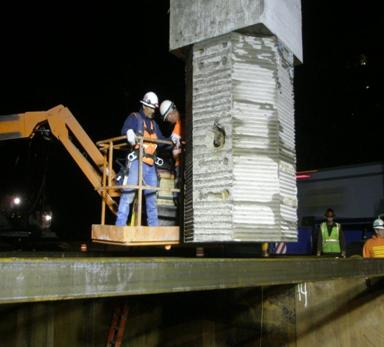 Figure 5. Photo. Socket connection concept, as originally used. A prototype square column with a circular socket connection is lowered into place during construction.