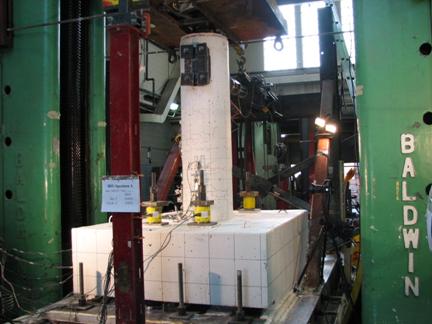 Figure 16. Photo. Testing in progress for spread footing specimens. A spread footing test specimen being tested in the test rig. Cracks in the column are visible.