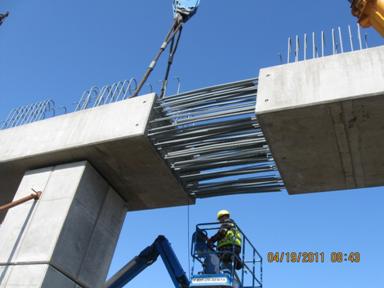Figure 53. Photo. Lowering the second lower-stage cap beam into place. Showing the congestion of rebar due to the lap splices from the reinforcing extending from either cap beam segment.