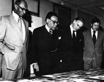 Viewing an Exhibit: Shortly after taking office, Secretary William T. Coleman, Jr., viewed FHWA's Black History Exhibit with Alexander G. Gaither (left), Director, FHWA's Office of Civil Rights; Deputy Secretary John W. Barnum; and FHWA Executive Director Lester P. Lamm (right). Turning to Deputy Secretary Barnum, Secretary Coleman said, 'John, we are going to make DOT the best Department in the entire Federal Government.' Secretary Coleman was enthusiastically applauded.