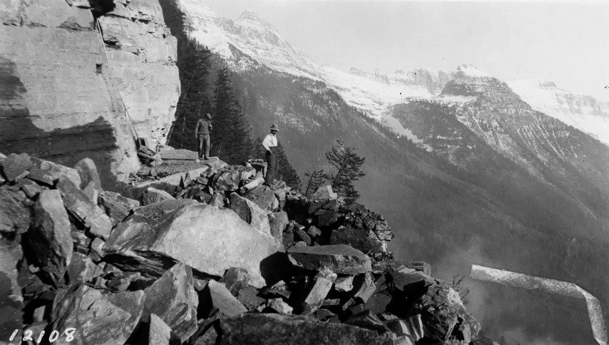 In Glacier National Park, engineers and crews building the Transmountain Highway (renamed the Going-to-the-Sun Road) confronted rugged conditions. This photograph from October 1925 shows two crew members standing on rocky terrain.  (National Park Service)