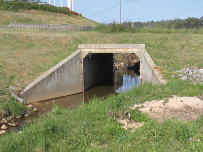 Photograph. A large concrete culvert crossing under a roadway.