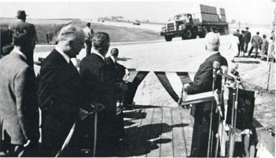 After ribbon cutting ceremony, first trucks roll over Loop 6(D) at the AASHO Road Test.  (See October 15, 1958)