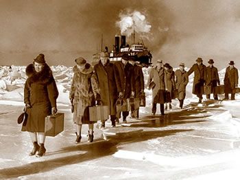 Passengers walk through snow with suitcases inhand.