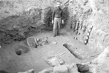 Archeologist standing in dig with artifacts.