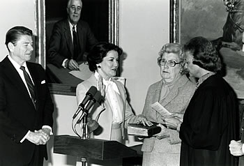 Supreme Court Justice Sandra Day O'Connor administers the oath of office to Secretary of Transportation Elizabeth Hanford Dole.  President Ronald Reagan looks on as Secretary Dole's mother, Mrs. Mary Hanford, holds the Bible.