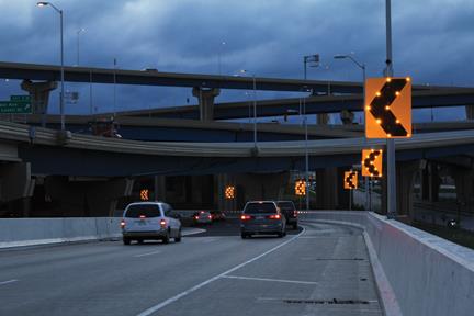 The photo depicts a Sequential Dynamic Curved Warning System consisting of a series of solar-powered, LED-enhanced BlinkerSigns® (a Curve Warning BlinkerSign and an array of Chevron BlinkerSigns) that are installed throughout a curve.
