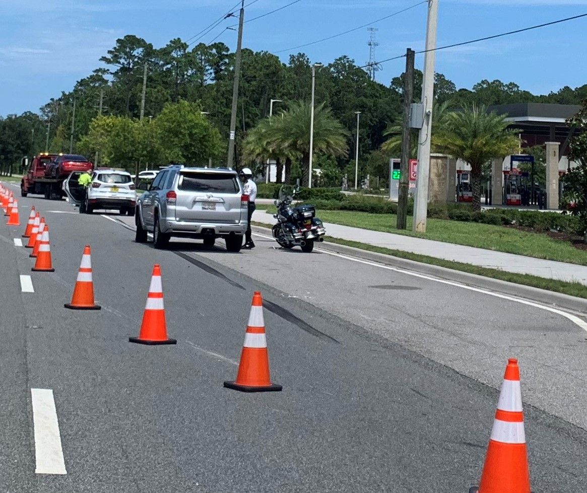 Orange cones in a row at a roadside traffic incident.